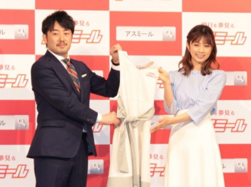 伊藤篤史取締役（左）とエプロンを渡される小倉優子